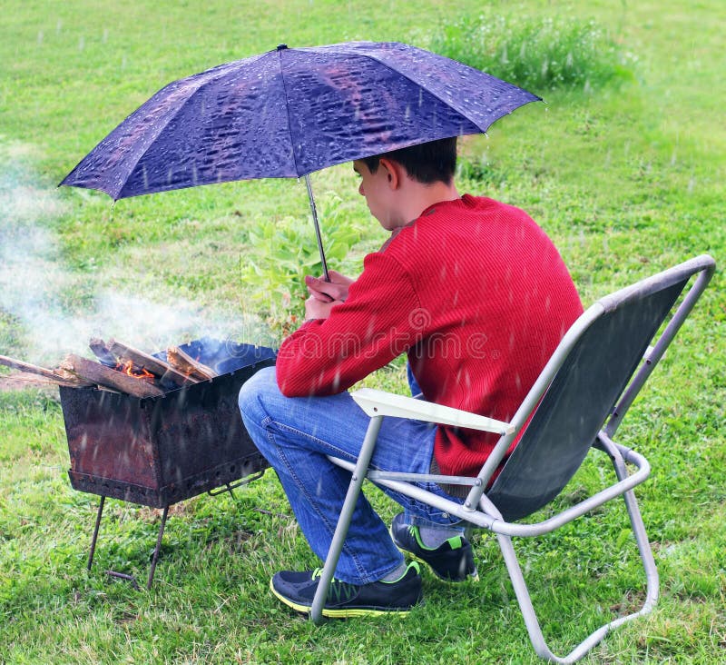 Teenager vuole cucinare shish kebab alla brace, nonostante il tempo piovoso.