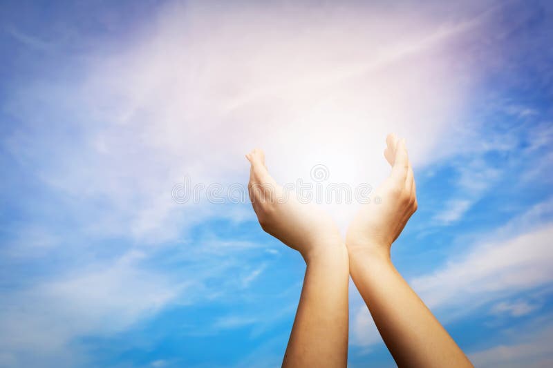 Raised hands catching sun on blue sky. Concept of spirituality