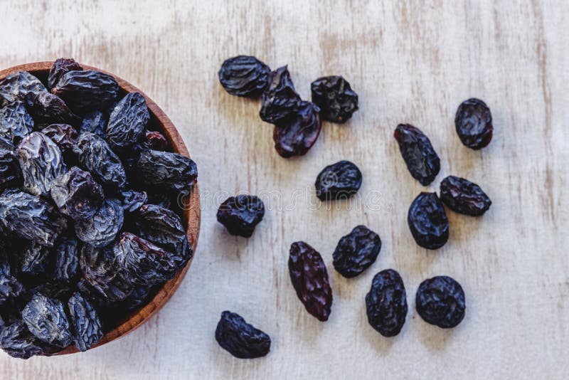 Dark Blue Raisins in a Wooden Bowl on a Bright White Background. Close ...