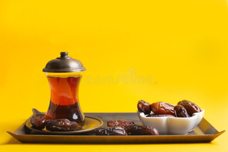 Ramadan Kareem Festival, Dates at bowl with a cup of black tea on yellow background