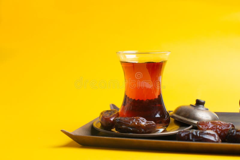 Ramadan Kareem Festival, Dates at bowl with a cup of black tea on yellow background