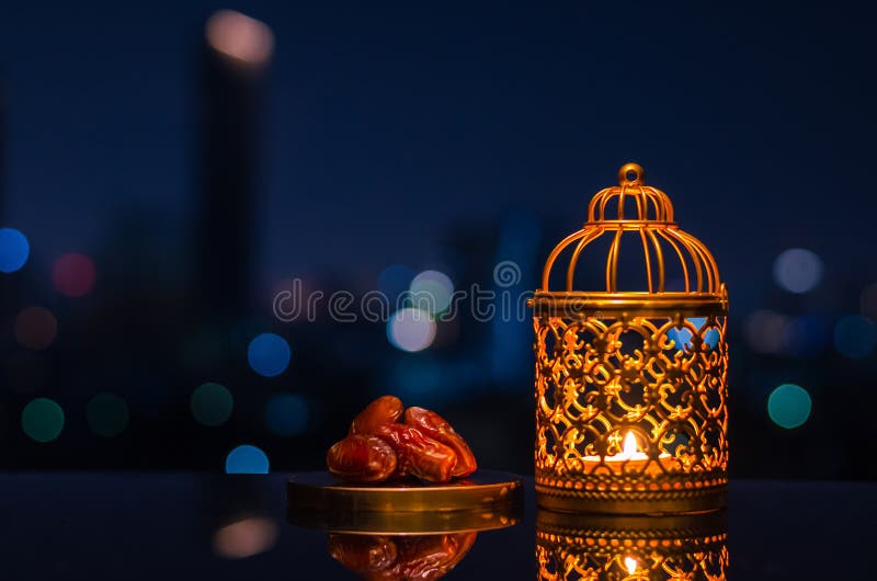 Ramadan Kareem lantern and dates fruit with city light background.