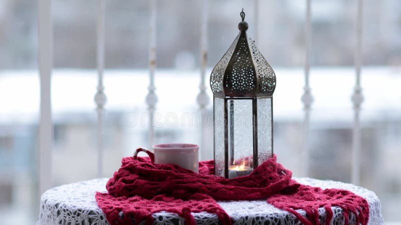 Ramadan lantern with candle inside and hot tea into mug with steam rising