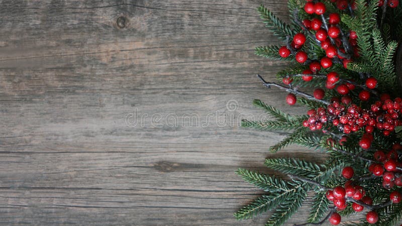 Rami e bacche sempreverdi di Natale sopra fondo orizzontale di legno rustico