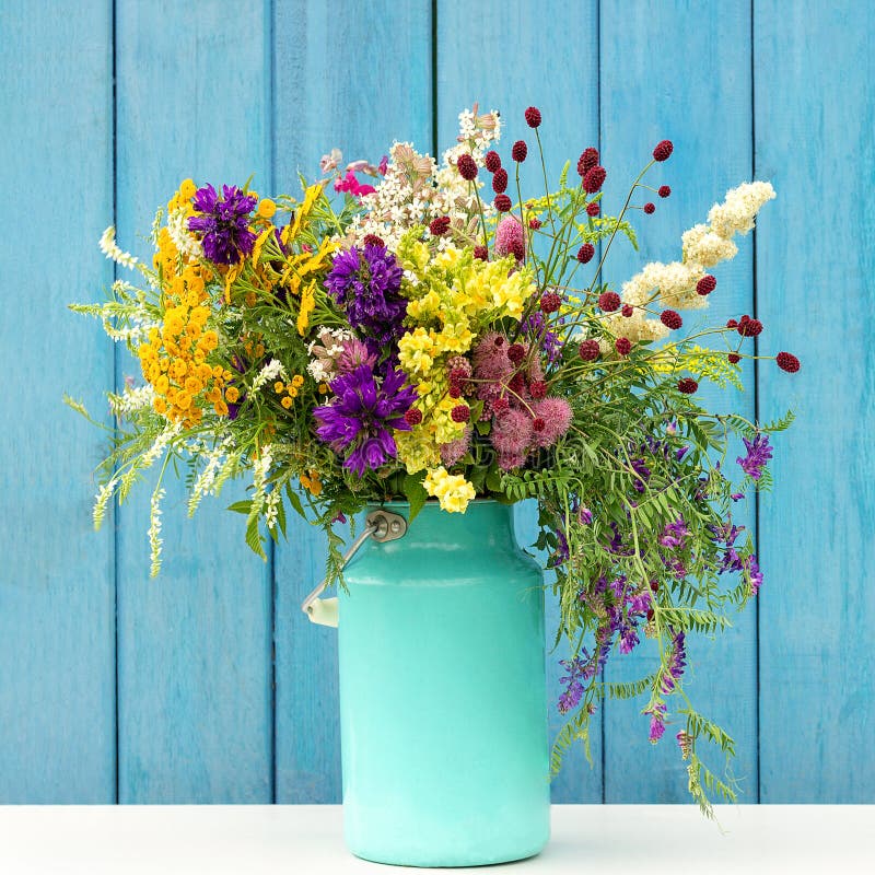 Ramo colorido brillante de flores salvajes en florero de la lata del starm en los tableros de madera azules del fondo Plantilla p imagen de archivo libre de regalías Ramo colorido brillante de flores salvajes en florero de la lata del starm en los tableros de madera azules del fondo Plantilla p imagen de archivo libre de regalías
