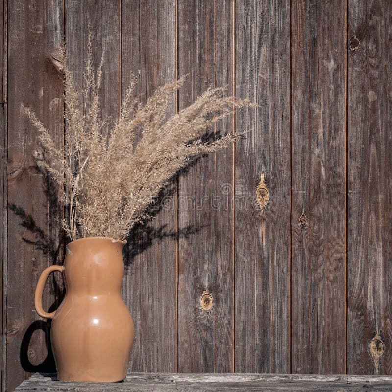 Ramo de hierbas secadas en un florero de cerámica en una tabla de madera en el franco. El ramo de hierbas secadas en un florero de cerámica en una tabla de madera delante de una pared vieja de madera