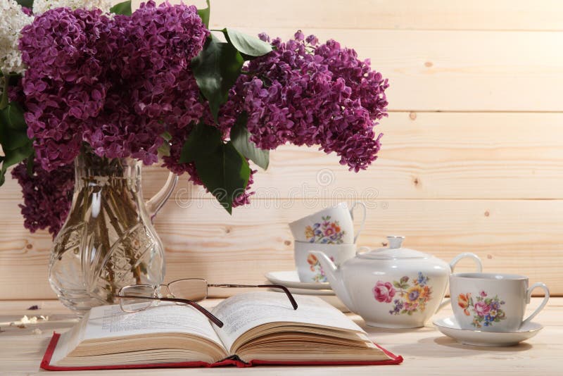 Ramo de lilas, de libro abierto, de gafas, de tetera y de taza de té imagenes de archivo Ramo de lilas, de libro abierto, de gafas, de tetera y de taza de té imagenes de archivo