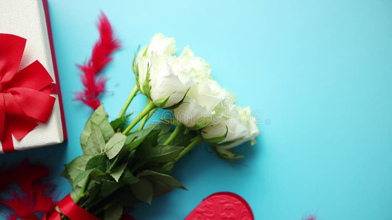 Ramo de rosas blancas con el arco rojo en fondo azul Regalo encajonado en lado