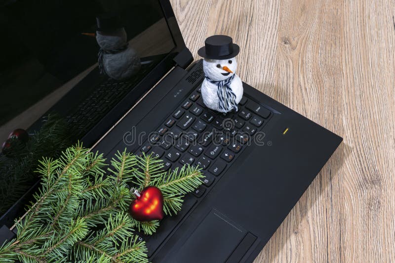 Ramo de árvore do laptop, do Natal e um boneco de neve em um de madeira foto de stock royalty free Ramo de árvore do laptop, do Natal e um boneco de neve em um de madeira foto de stock royalty free