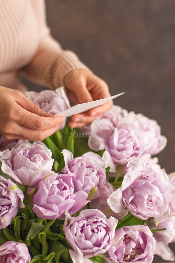 Ramo grande hermoso de flores violetas dobles del tulipán con la tarjeta de felicitación en blanco en un fondo oscuro del rustik imagen de archivo libre de regalías Ramo grande hermoso de flores violetas dobles del tulipán con la tarjeta de felicitación en blanco en un fondo oscuro del rustik imagen de archivo libre de regalías