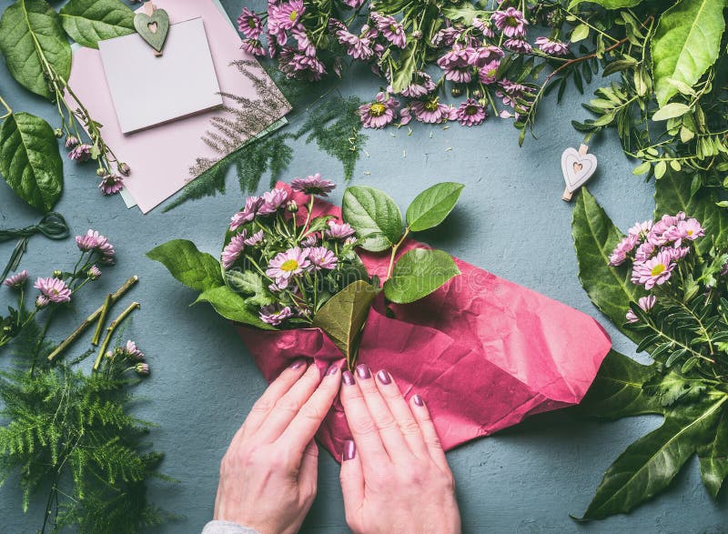 Ramo precioso del abrigo femenino de la mano de flores rosadas en documento de embalaje sobre el espacio de trabajo del florista, fotografía de archivo Ramo precioso del abrigo femenino de la mano de flores rosadas en documento de embalaje sobre el espacio de trabajo del florista, fotografía de archivo