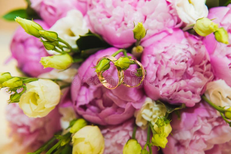 Ramo que se casa delicado hermoso de peonías y de anillos de bodas rosados de la novia y del novio imagenes de archivo Ramo que se casa delicado hermoso de peonías y de anillos de bodas rosados de la novia y del novio imagenes de archivo