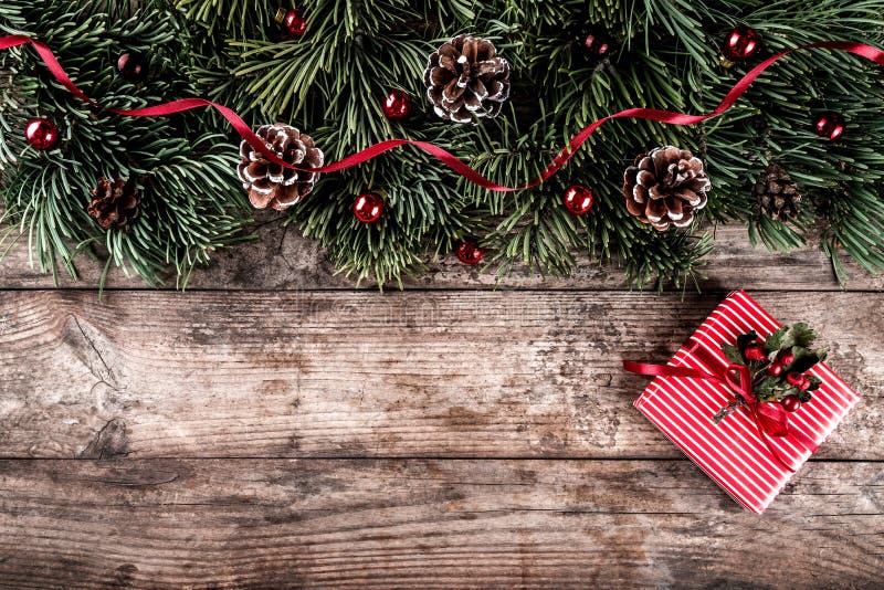 Ramos do abeto do Natal no fundo de madeira do feriado com caixas de presente, cones do pinho, decoração vermelha imagens de stock royalty free Ramos do abeto do Natal no fundo de madeira do feriado com caixas de presente, cones do pinho, decoração vermelha imagens de stock royalty free