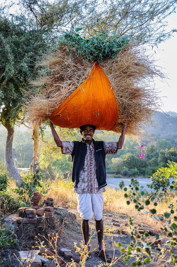 Ranakpur, India - Jan 02, 2020: Indian man carries hay on his head. Ranakpur, India - Jan 02, 2020: Indian man carries hay on his head.