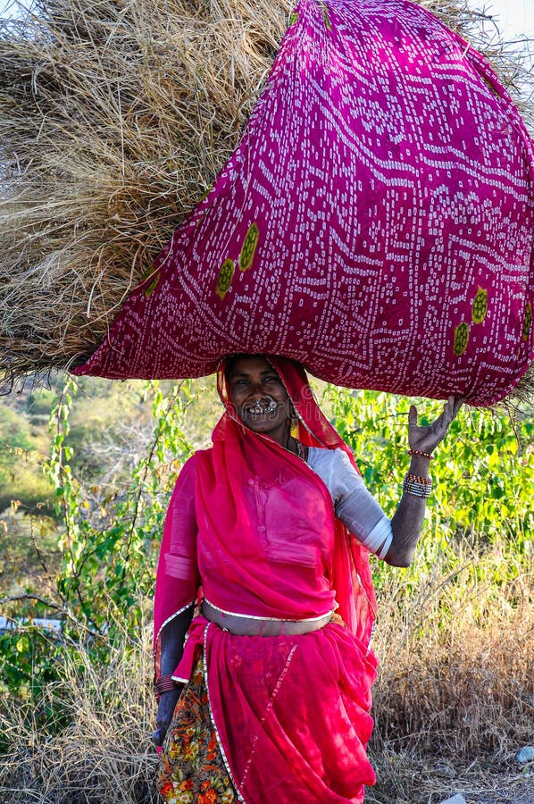 Ranakpur, India - Jan 02, 2020: Indian woman carries hay on her head. Ranakpur, India - Jan 02, 2020: Indian woman carries hay on her head.