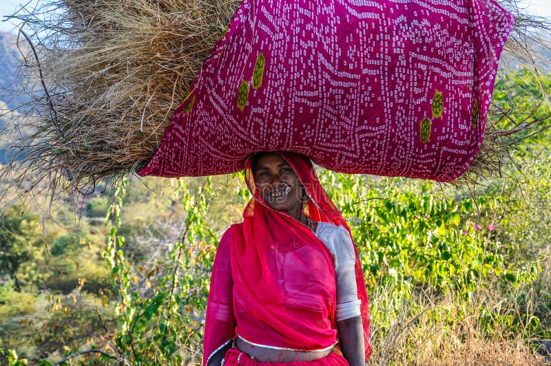 Ranakpur, India - Jan 02, 2020: Indian woman carries hay on her head. Ranakpur, India - Jan 02, 2020: Indian woman carries hay on her head.