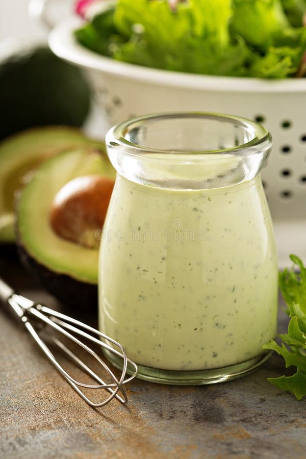 Homemade avocado ranch dressing in a small jar with fresh greens. Homemade avocado ranch dressing in a small jar with fresh greens