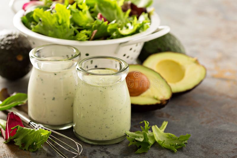 Avocado ranch dressing in small jar with salad leaves in a collander. Avocado ranch dressing in small jar with salad leaves in a collander