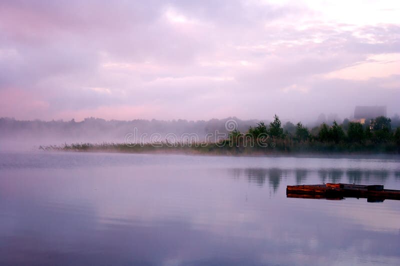 Morning nature scene (landscape): fog (mist) reflected in the water surface along with reeds, pink and blue sky, trees and a home on the shore and moorage (quay, berth, wharf). The Seliger lake (Russia). Can be used as a background (backdrop) or wallpaper. Morning nature scene (landscape): fog (mist) reflected in the water surface along with reeds, pink and blue sky, trees and a home on the shore and moorage (quay, berth, wharf). The Seliger lake (Russia). Can be used as a background (backdrop) or wallpaper.