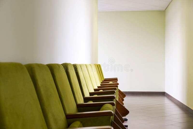 Rangée d'amphithéâtre vert posant les chaises molles avec des blocs - notes placés le long du mur dans le couloir Affaires ou évé photos stock Rangée d'amphithéâtre vert posant les chaises molles avec des blocs - notes placés le long du mur dans le couloir Affaires ou évé photos stock
