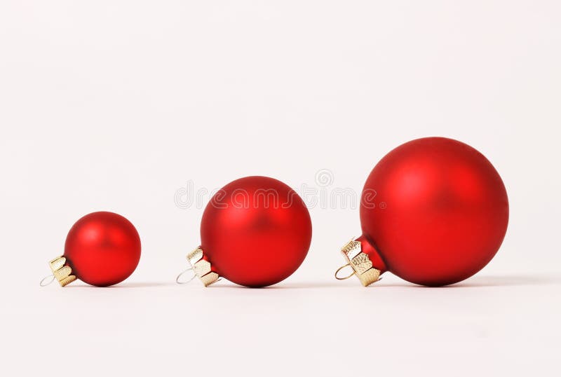 Row of three red matt different sizes christmas balls on white background - horizontal. Row of three red matt different sizes christmas balls on white background - horizontal
