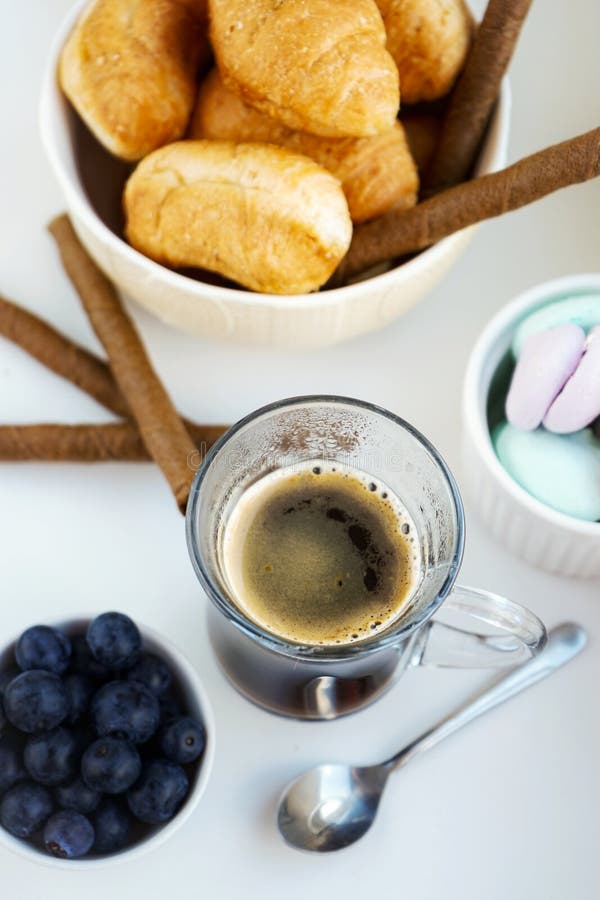 ranku Śniadaniowy filiżanka kawy, croissants, barwione słodkie bezy, czarne jagody w glinianym białym szkle zdjęcia stock ranku Śniadaniowy filiżanka kawy, croissants, barwione słodkie bezy, czarne jagody w glinianym białym szkle zdjęcia stock