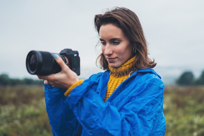 Rapariga turista de fotografia na capa de chuva azul segura em mãos fotocâmera fotográfica fotografar montanha de sapo foto de stock royalty free Rapariga turista de fotografia na capa de chuva azul segura em mãos fotocâmera fotográfica fotografar montanha de sapo foto de stock royalty free