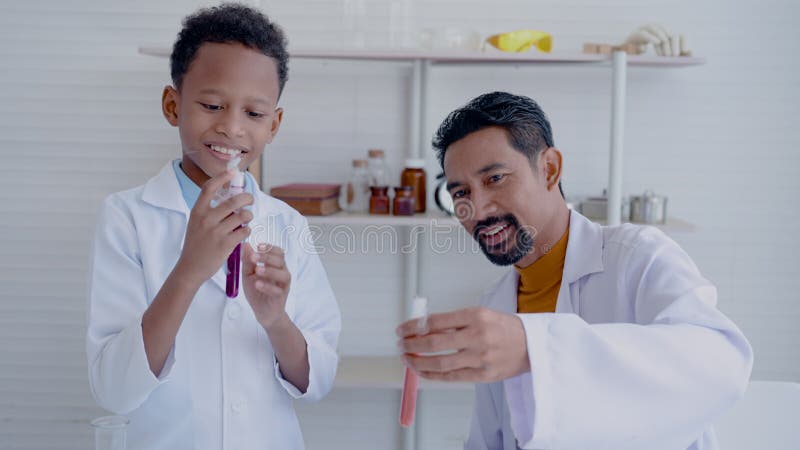 Rapaz de 4k chama a atenção para tubos multicoloridos de testes de ciência com professor na sala de ciência branca de sua escola p