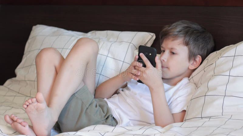 retrato cenimatic menino jogando no celular enquanto espera por comida,  garoto sentado no café enviando texto para amigos, criança jogando jogo  online no telefone. 9711757 Foto de stock no Vecteezy