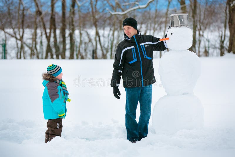 Rapaz pequeno com seu pai que faz um boneco de neve fotos de stock royalty free