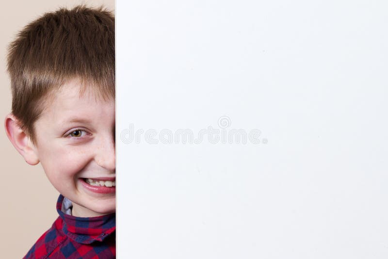 Rapaz pequeno de sorriso feliz, mostrando o cartaz vazio branco, placa, posição fotografia de stock royalty free Rapaz pequeno de sorriso feliz, mostrando o cartaz vazio branco, placa, posição fotografia de stock royalty free