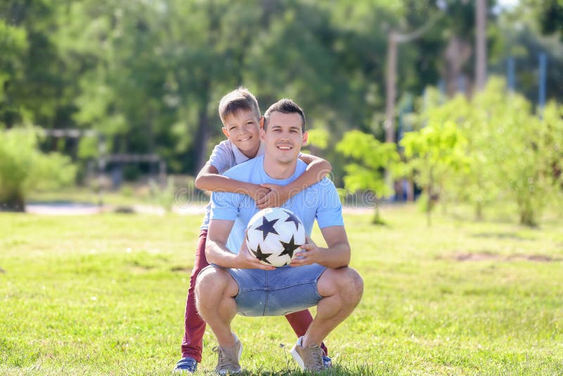 Rapaz pequeno e seu paizinho com bola de futebol fora imagem de stock Rapaz pequeno e seu paizinho com bola de futebol fora imagem de stock