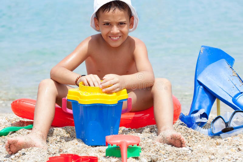 Rapaz pequeno na praia tropical que joga na areia imagem de stock Rapaz pequeno na praia tropical que joga na areia imagem de stock