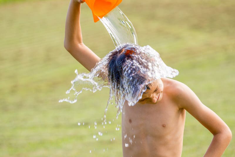 Rapaz pequeno que derrama a água fria em sua cabeça fora foto de stock Rapaz pequeno que derrama a água fria em sua cabeça fora foto de stock