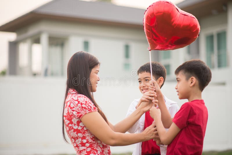Rapazes pequenos que dão o coração do balão a seu amor de mãe foto de stock royalty free Rapazes pequenos que dão o coração do balão a seu amor de mãe foto de stock royalty free