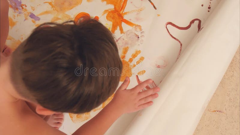 Rapazes pequenos que pintam com suas palmas no papel foto de stock