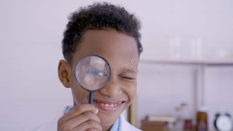 Rapazinho asiático de 4k presta atenção a uma lupa com um sorriso feliz no seu soquete de olhos em suas escolas elementares branco