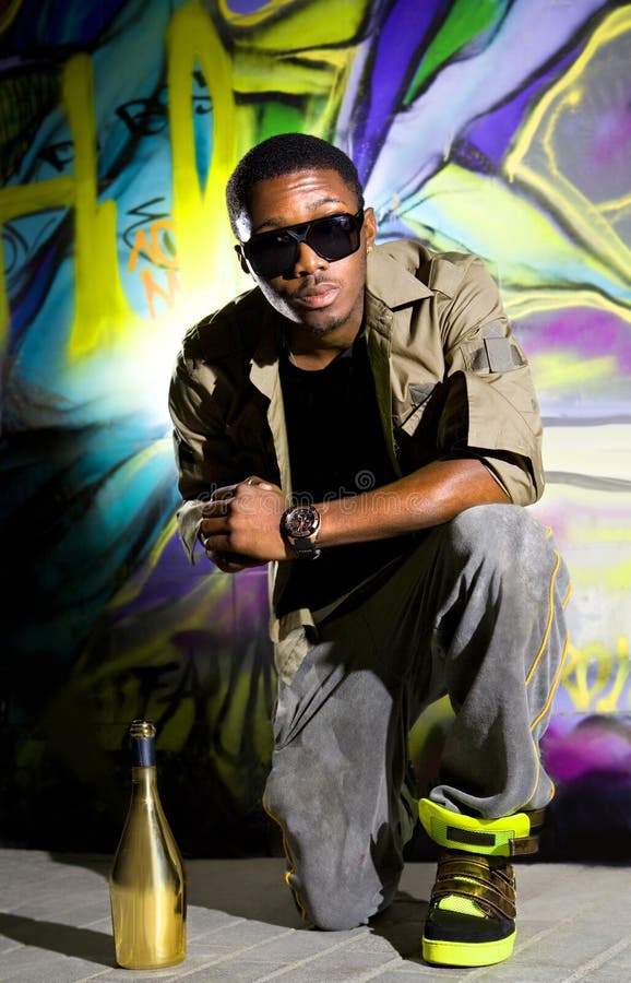 Young afro-american man sitting in front of colorful graffiti wall. Young afro-american man sitting in front of colorful graffiti wall