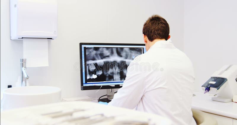 Rapporto d'esame dei raggi x del dentista attento sul computer