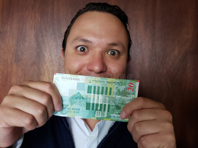 rappresentazione del giovane e tenere una banconota israeliana di venti shekel immagini stock libere da diritti rappresentazione del giovane e tenere una banconota israeliana di venti shekel immagini stock libere da diritti