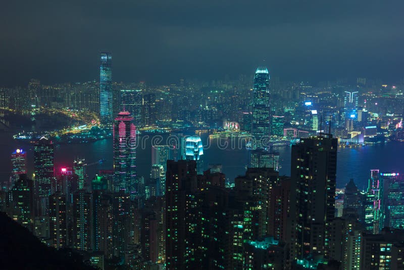 Night scene of Hong Kong city taken from Victoria Peak showing lit up skyscrapers and Victoria Harbor. Lights of blue and green glow leave cyberpunk feel. Night scene of Hong Kong city taken from Victoria Peak showing lit up skyscrapers and Victoria Harbor. Lights of blue and green glow leave cyberpunk feel.