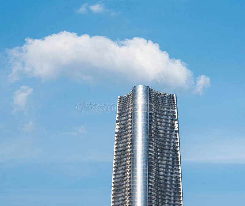Rascacielos moderno contra cielo azul claro con nubes imagen de archivo