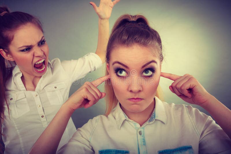 Conflict, bad relationships, friendship difficulties. Two young women having argument. Angry fury girl screaming at her friend or younger sister, female closing his ears, not listening. Conflict, bad relationships, friendship difficulties. Two young women having argument. Angry fury girl screaming at her friend or younger sister, female closing his ears, not listening