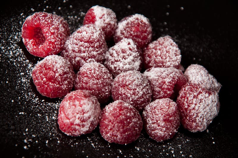 Raspberries with a sugar powder on a black