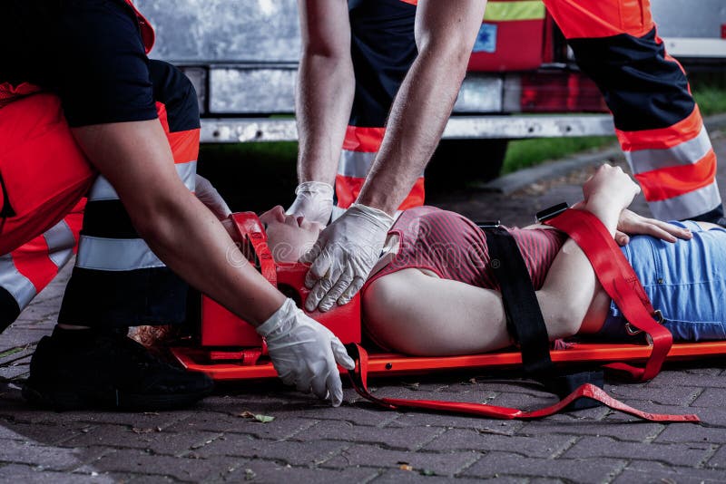 Ratownik medyczny zginający nad ofiarą wypadku samochodowego leżącą na noszach