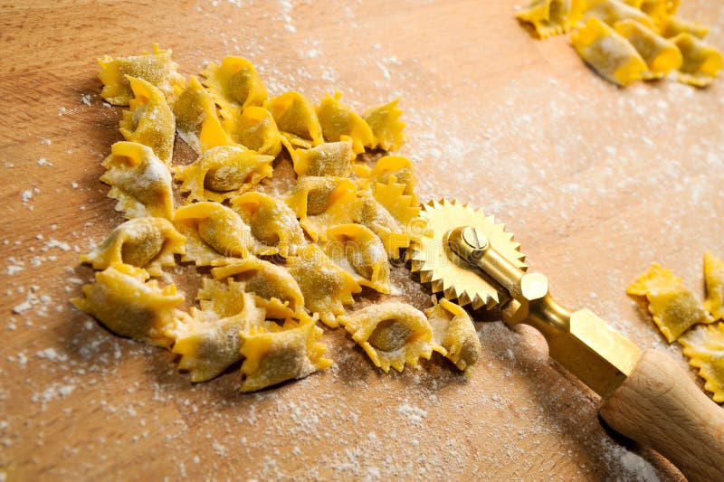 Ravioli del plin, typical pasta from Langhe, Piedmont, Italy - agnolotti with wheel knife on wooden cutting board. Ravioli del plin, typical pasta from Langhe, Piedmont, Italy - agnolotti with wheel knife on wooden cutting board