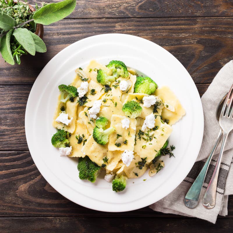 Italian ravioli with goat cheese, broccoli and herbs on old wooden background. Healthy food. Top view. Italian ravioli with goat cheese, broccoli and herbs on old wooden background. Healthy food. Top view.
