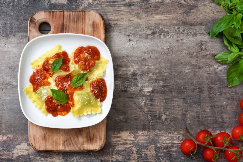 Ravioli with tomato sauce and basil on wooden background. Top view. Ravioli with tomato sauce and basil on wooden background. Top view