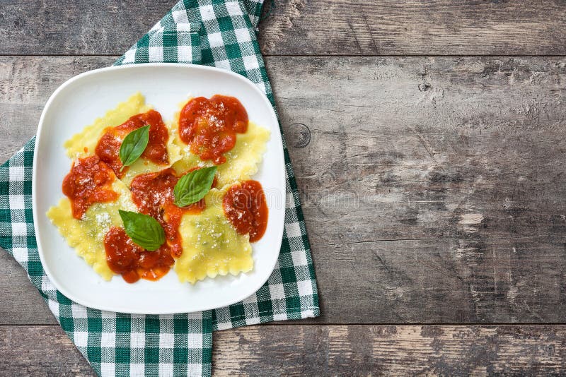 Ravioli with tomato sauce and basil on wooden background. Top view. Ravioli with tomato sauce and basil on wooden background. Top view