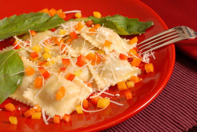 Ravioli topped with diced red, yellow and orange peppers with ba